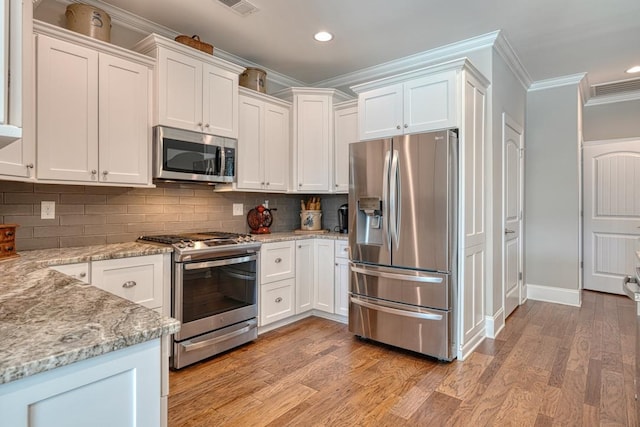 kitchen with white cabinetry, light stone counters, stainless steel appliances, and crown molding