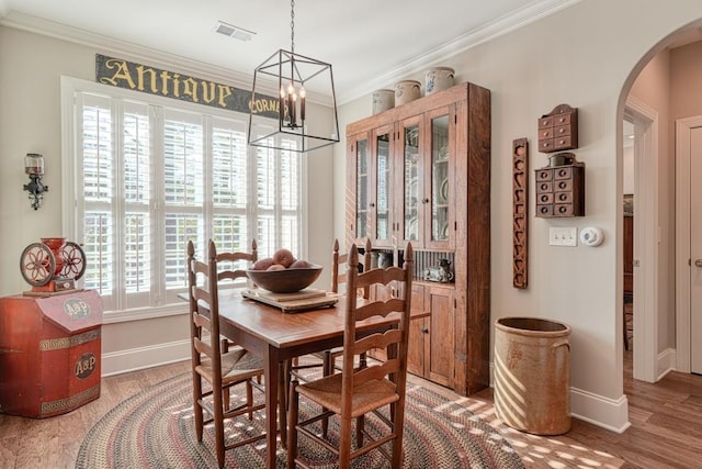 dining room with hardwood / wood-style floors, crown molding, plenty of natural light, and a chandelier