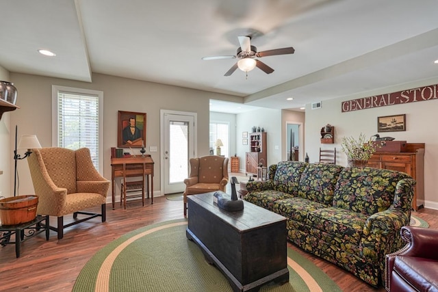 living room featuring dark wood-type flooring, ceiling fan, and a wealth of natural light