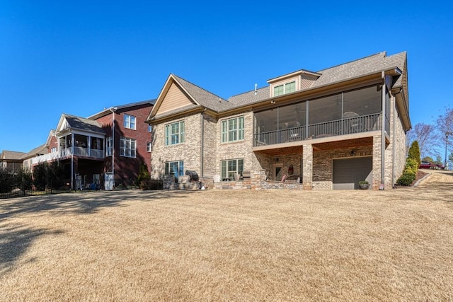 rear view of property featuring a garage and a sunroom