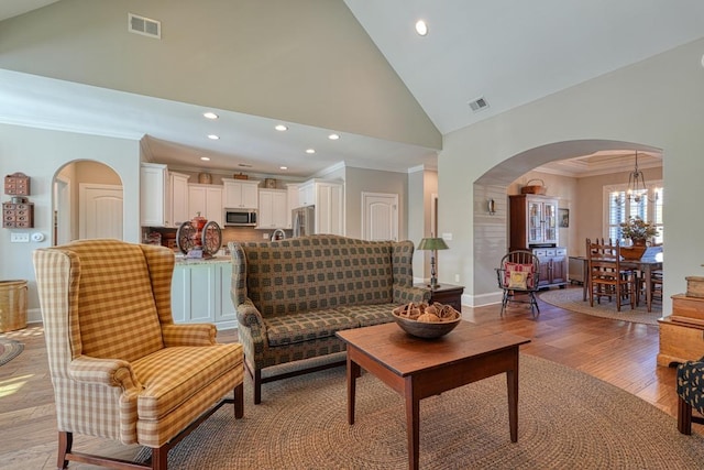 living room featuring ornamental molding, an inviting chandelier, high vaulted ceiling, and light hardwood / wood-style flooring