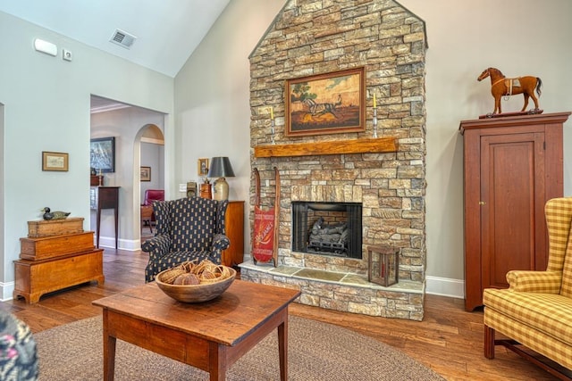 living room featuring wood-type flooring, a fireplace, and high vaulted ceiling