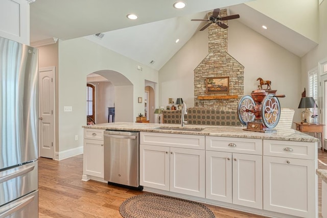 kitchen with sink, light stone countertops, white cabinets, and appliances with stainless steel finishes