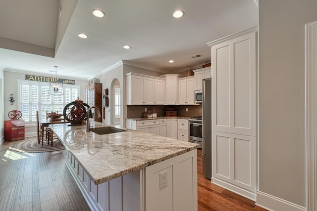 kitchen with pendant lighting, white cabinetry, sink, a large island, and dark wood-type flooring