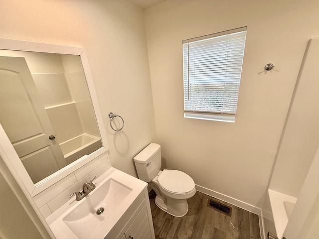 bathroom featuring wood-type flooring, a bath, vanity, and toilet