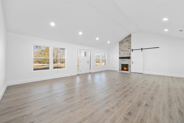 unfurnished living room with a fireplace, high vaulted ceiling, and light wood-type flooring