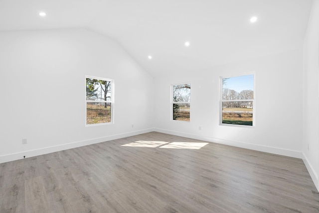 empty room featuring lofted ceiling, a healthy amount of sunlight, and light wood-type flooring