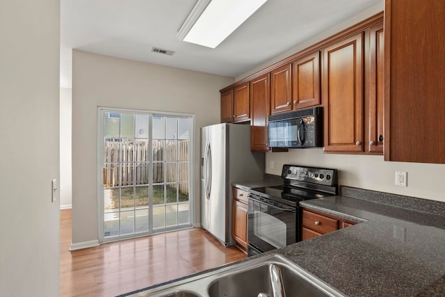 kitchen with black appliances and light hardwood / wood-style floors