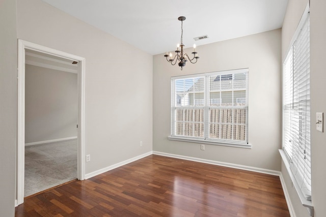 spare room featuring dark hardwood / wood-style floors and a notable chandelier