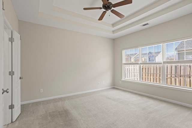 carpeted empty room featuring ceiling fan and a tray ceiling