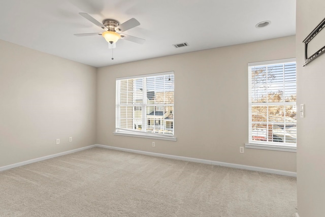 carpeted spare room featuring ceiling fan and a wealth of natural light