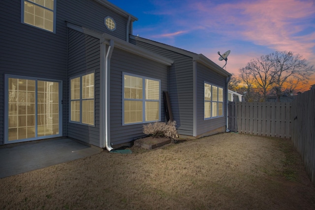 property exterior at dusk featuring a lawn