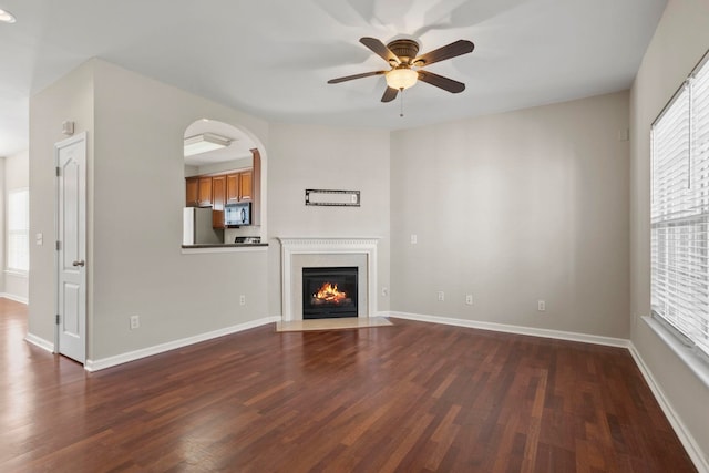 unfurnished living room featuring dark wood-type flooring and ceiling fan