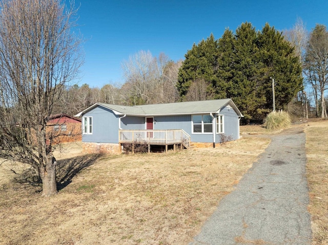 manufactured / mobile home featuring a wooden deck and a front yard