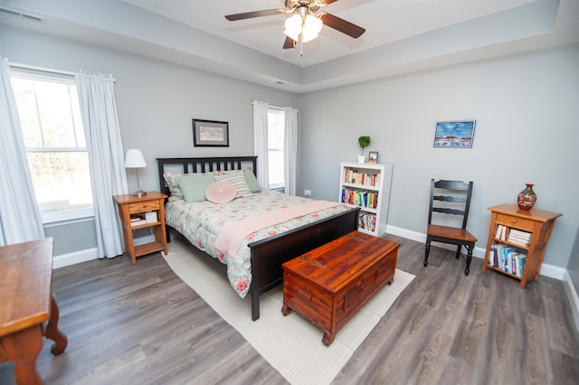 bedroom featuring a tray ceiling, dark wood-type flooring, and ceiling fan