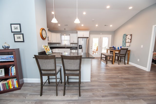 kitchen featuring pendant lighting, hardwood / wood-style flooring, a breakfast bar area, stainless steel refrigerator with ice dispenser, and white cabinets