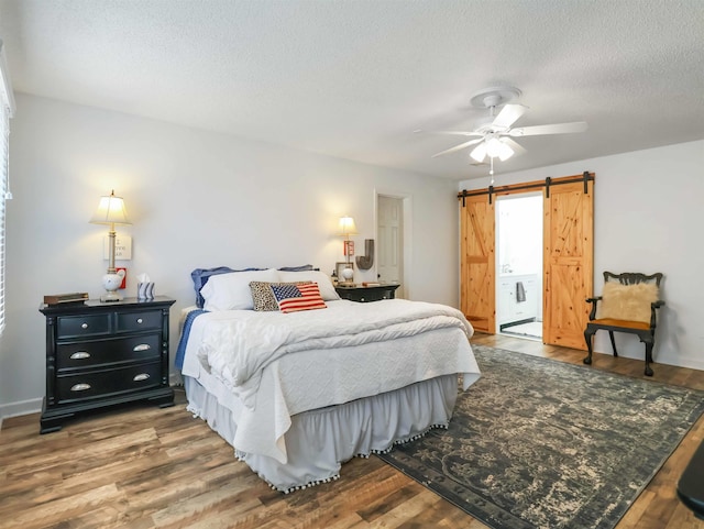 bedroom with ceiling fan, hardwood / wood-style flooring, a barn door, and a textured ceiling