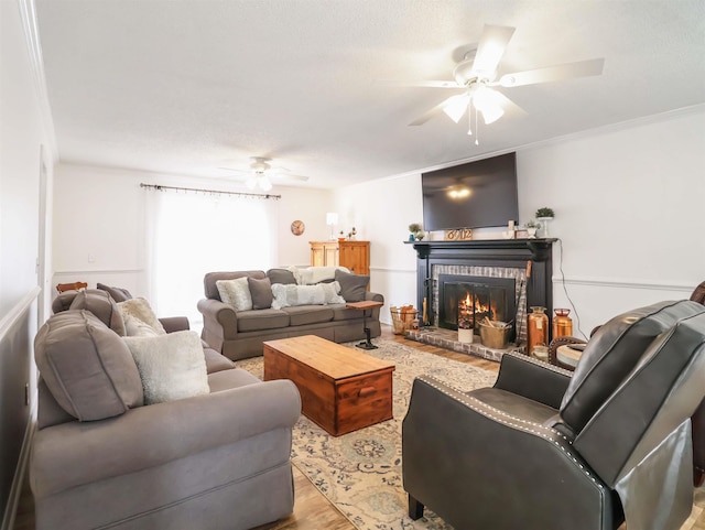 living room featuring crown molding, ceiling fan, light hardwood / wood-style floors, and a brick fireplace