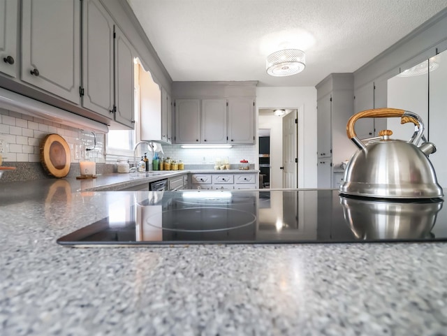 kitchen with a textured ceiling, sink, decorative backsplash, and gray cabinetry