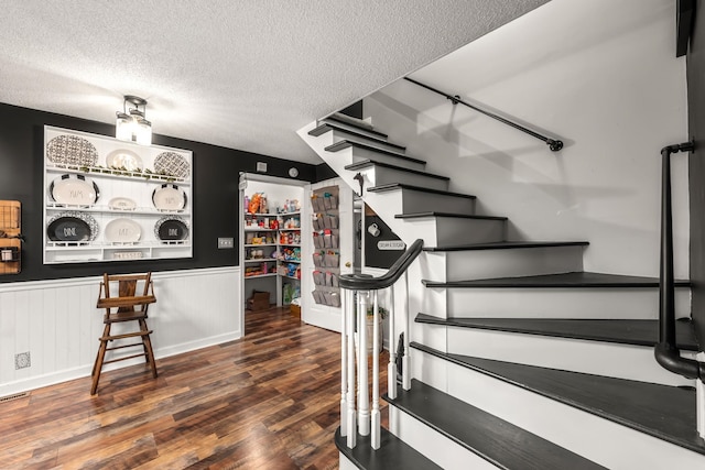 staircase with hardwood / wood-style floors and a textured ceiling