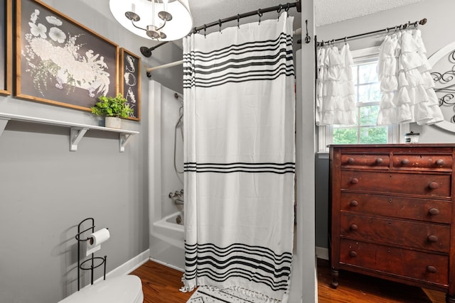 bathroom featuring wood-type flooring, shower / tub combo with curtain, a textured ceiling, and toilet