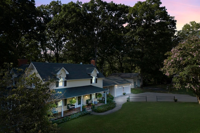 view of front facade with a yard, covered porch, and a garage