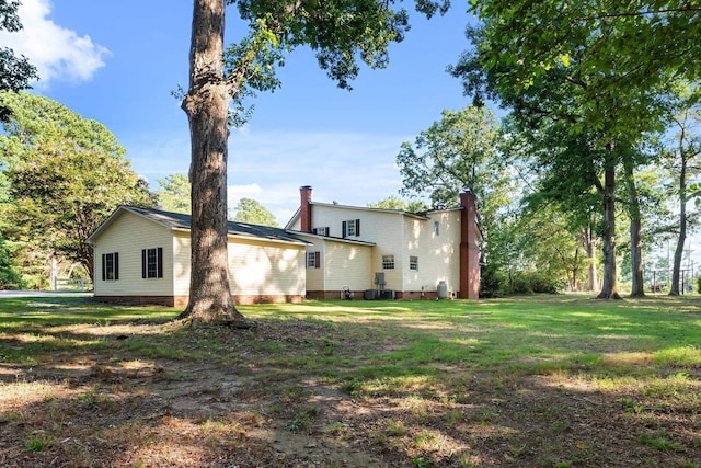 back of property featuring a lawn and central air condition unit