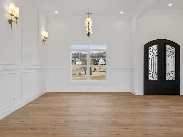 entryway featuring crown molding, light hardwood / wood-style flooring, and french doors