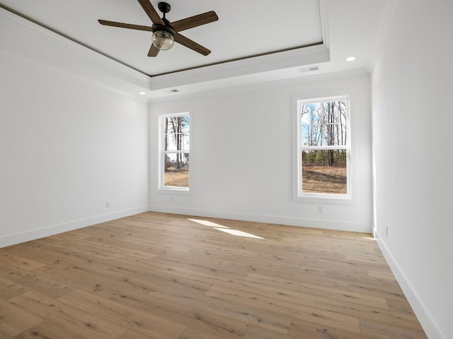 unfurnished room featuring ornamental molding, light wood-type flooring, and a tray ceiling