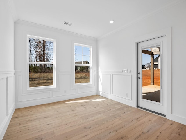 empty room with crown molding and light hardwood / wood-style floors