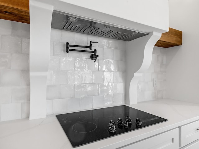 kitchen featuring white cabinetry, black electric stovetop, light stone countertops, and custom range hood