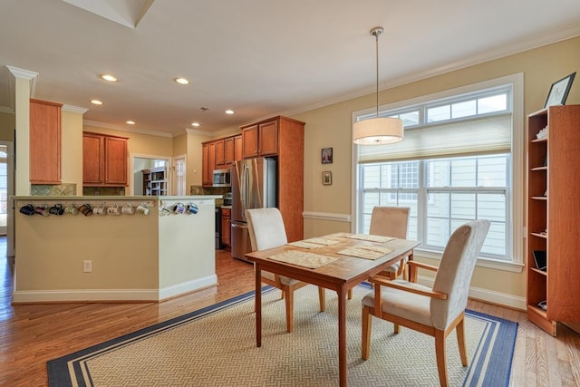 dining area with crown molding and light hardwood / wood-style floors