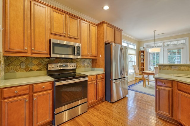 kitchen featuring decorative light fixtures, backsplash, ornamental molding, stainless steel appliances, and light wood-type flooring