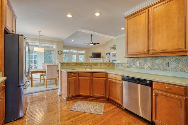 kitchen with sink, crown molding, appliances with stainless steel finishes, kitchen peninsula, and decorative backsplash