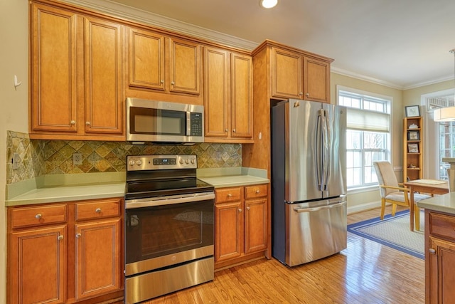 kitchen with backsplash, crown molding, stainless steel appliances, and light wood-type flooring