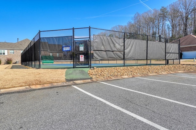 view of car parking featuring tennis court