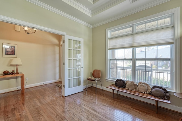 living area featuring crown molding, a tray ceiling, light hardwood / wood-style floors, and french doors