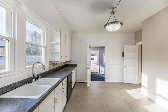 kitchen with white cabinetry, hanging light fixtures, sink, and black dishwasher