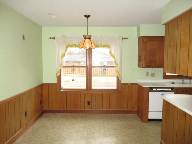 kitchen with dishwasher, sink, wood walls, and decorative light fixtures