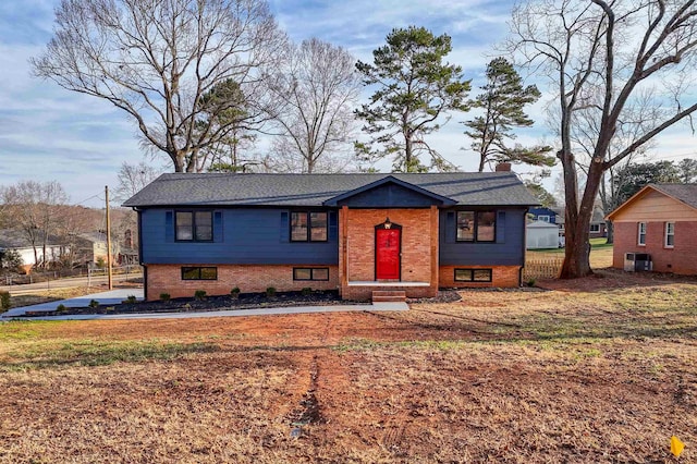 split foyer home with central AC unit and a front lawn