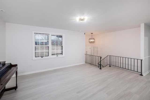 unfurnished room with a notable chandelier and light wood-type flooring