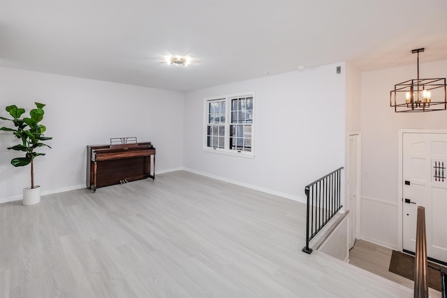 empty room with an inviting chandelier and light hardwood / wood-style flooring