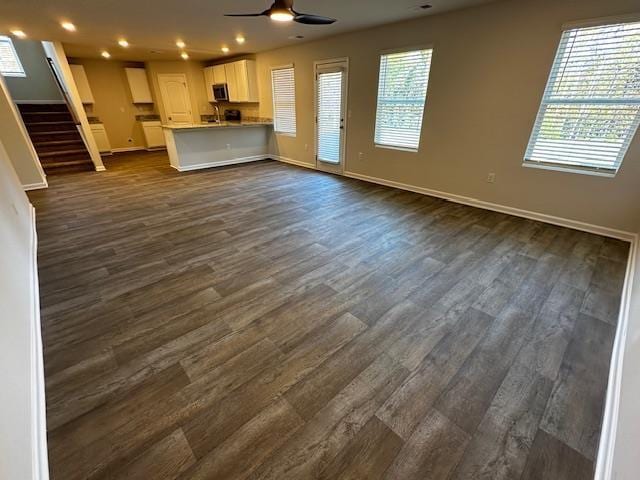 unfurnished living room with dark wood-type flooring and ceiling fan