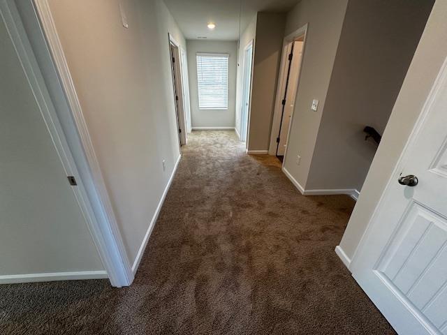 corridor featuring dark colored carpet