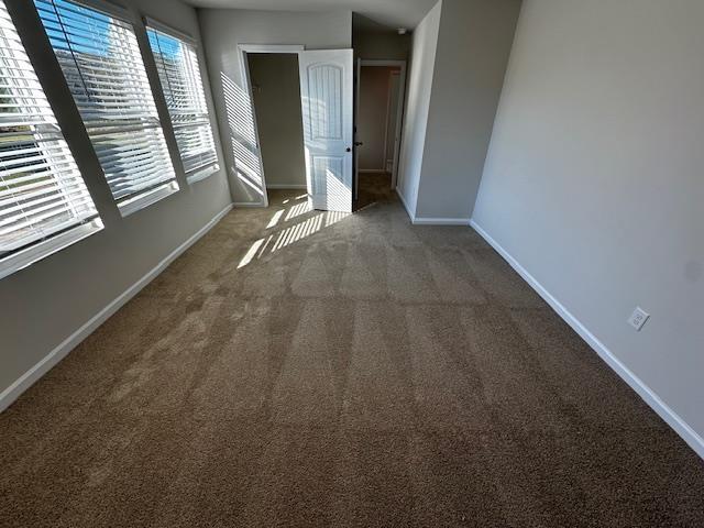 unfurnished bedroom with dark carpet