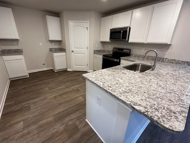 kitchen featuring black electric range oven, sink, kitchen peninsula, and white cabinets