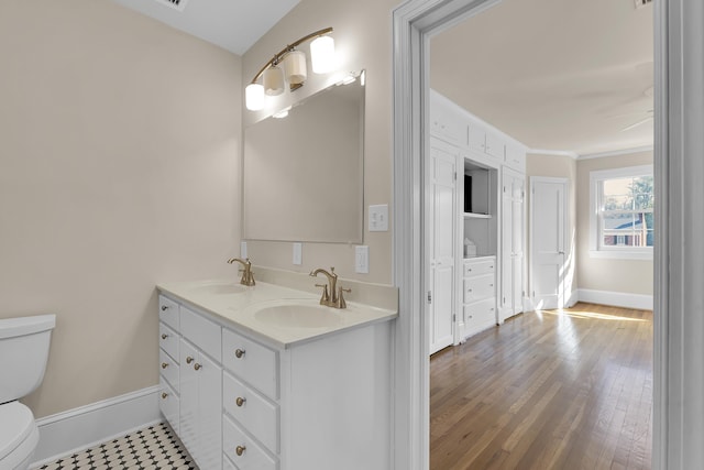 bathroom featuring hardwood / wood-style flooring, ceiling fan, vanity, ornamental molding, and toilet