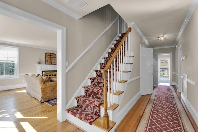 stairs with ornamental molding, wood-type flooring, and a wealth of natural light