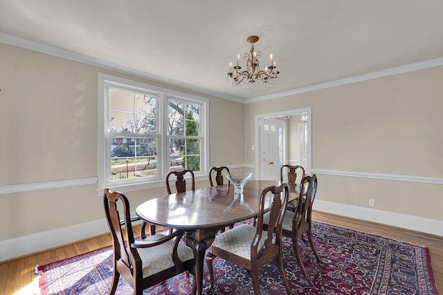 dining room with hardwood / wood-style flooring, crown molding, and a notable chandelier