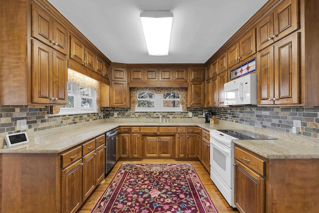 kitchen with sink, white appliances, light stone counters, decorative backsplash, and light wood-type flooring